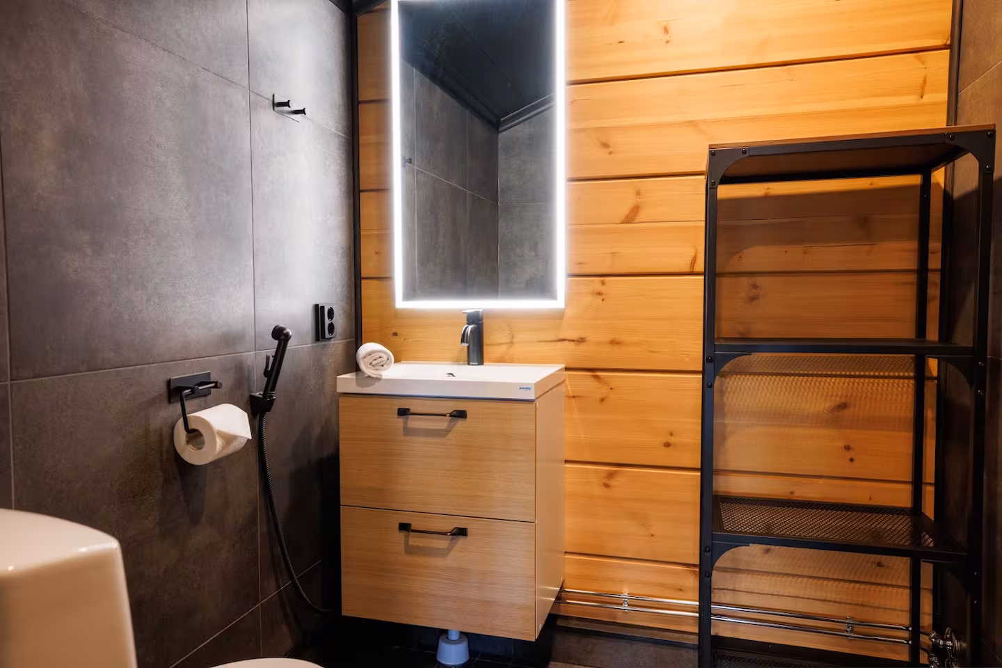 Modern bathroom with a backlit mirror, wood vanity and walk-in shower