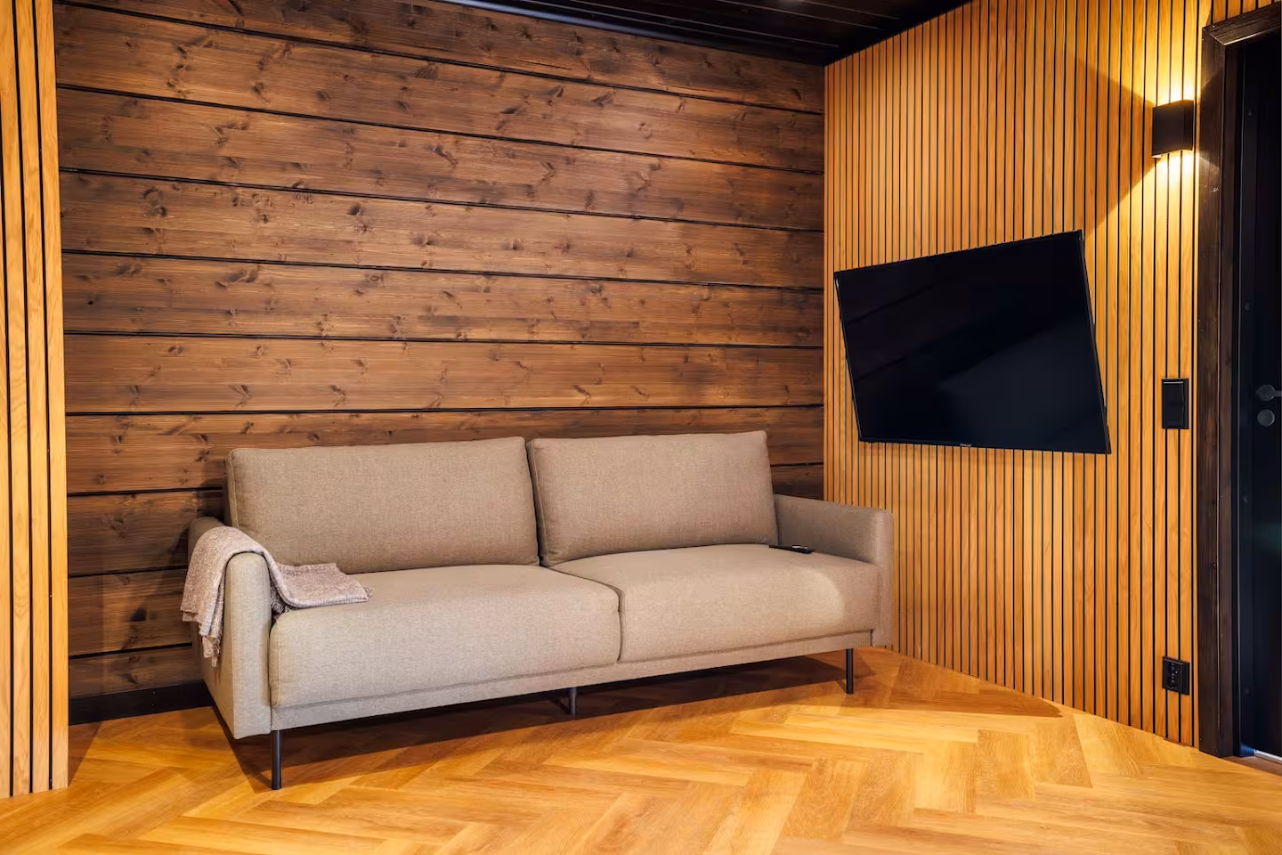 Small lounge with a fabric sofa, wall-mounted television and timber panelling