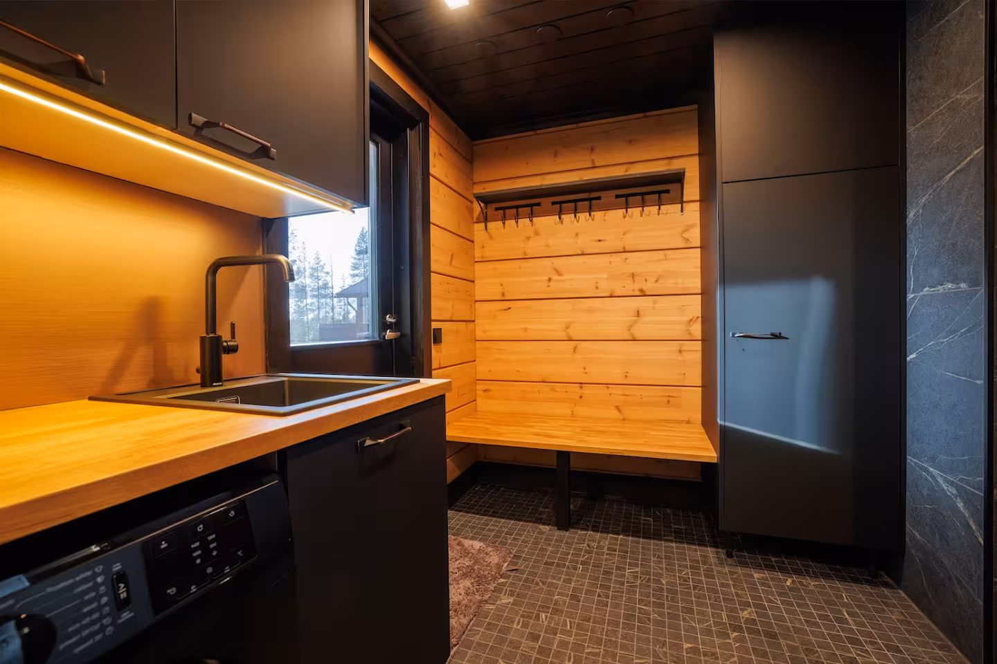 Utility room with washing machine, sink and a timber drying bench for ski gear