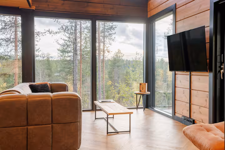 Leather sofa and bench in a glazed corner overlooking autumn pine forest