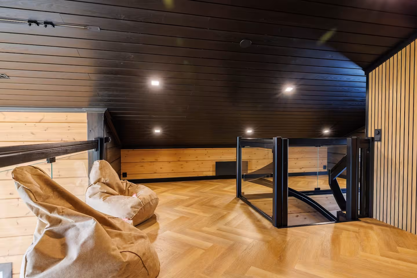 Loft space under a black-panelled pitched roof with beanbag seating